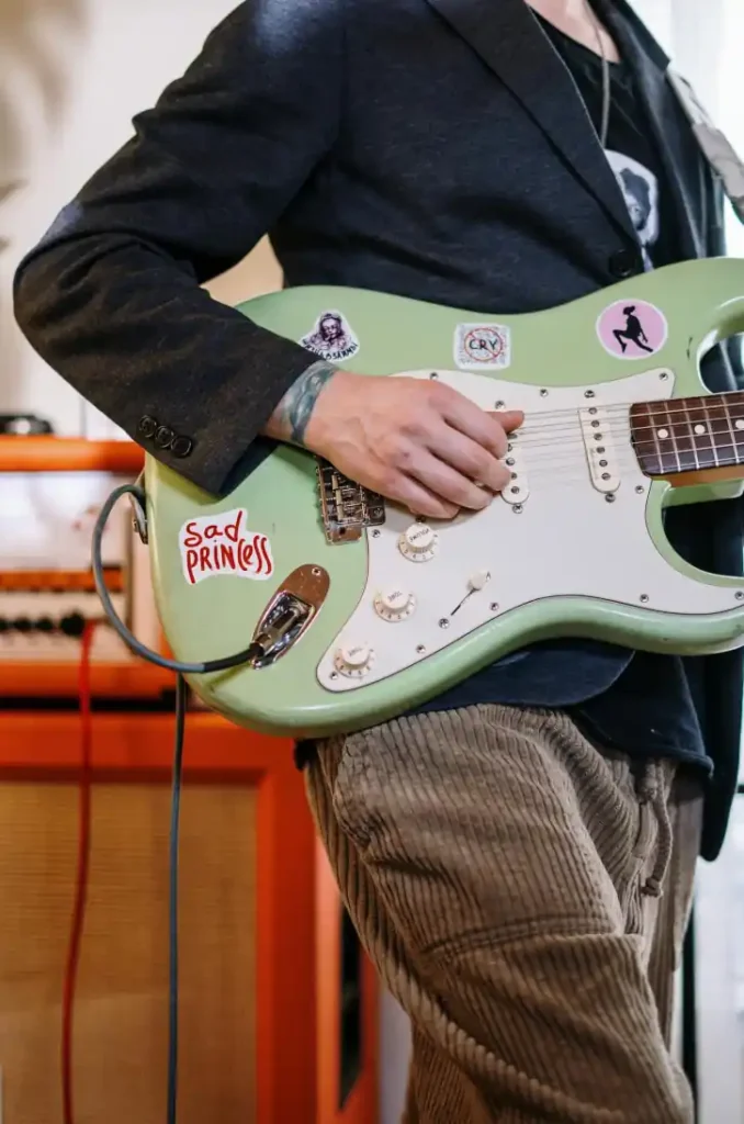 Gitarzysta elegancko ubrany gra na miętowej gitarze elektrycznej.