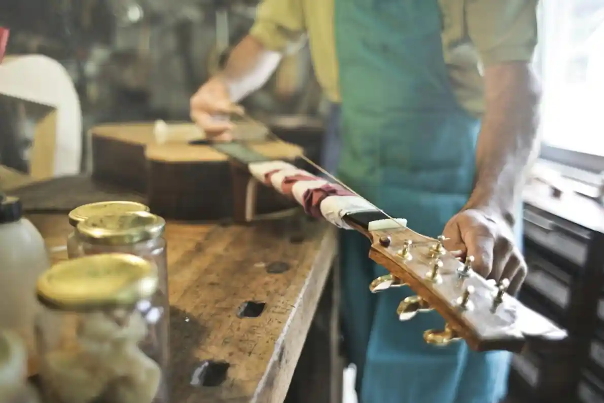 Praca lutnika gitarowego, który wymienia struny i konserwuje gitarę.